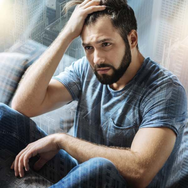 Man sat on floor looking anxious and dejected, struggling with addiction.