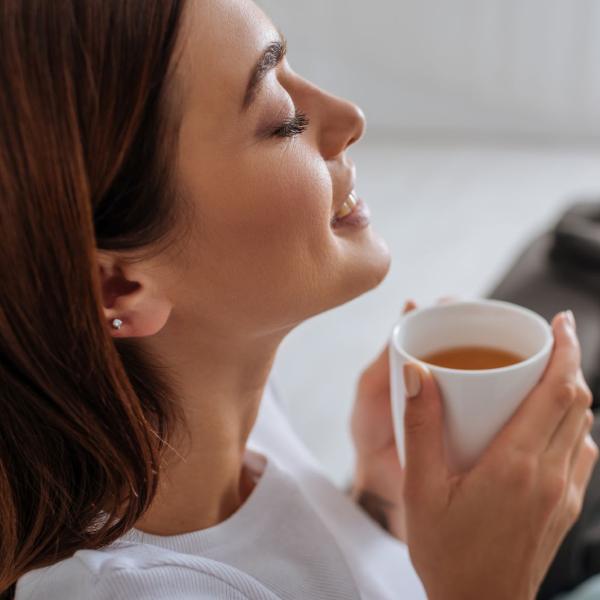 Woman looking calm and peaceful, taking time out for a mindful moment , enjoying a cup of tea meditation style with concentration and relaxation.